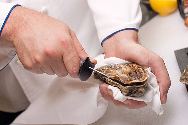 Close-up of hands shucking an oyster stock photo