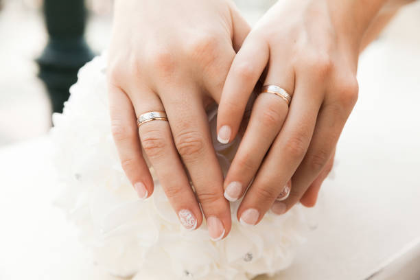 Closeup Of Hands With Wedding Rings Of Two Brides stock photo