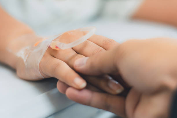 Closeup of husband holding patients hand in hospital,Patients saline, Iv drip, hand with medical drip intravenous needle, give salt water on hospital. stock photo