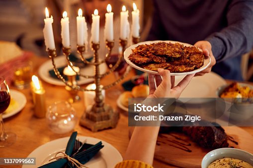 istock Close-up of Jewish couple passing food at dining table on Hanukkah. 1337099562