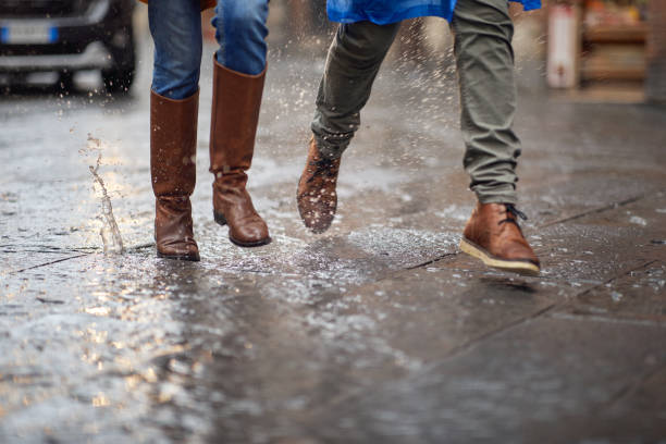 Close-up of legs of a young couple walking on the rain in the city. Walk, rain, city, relationship stock photo