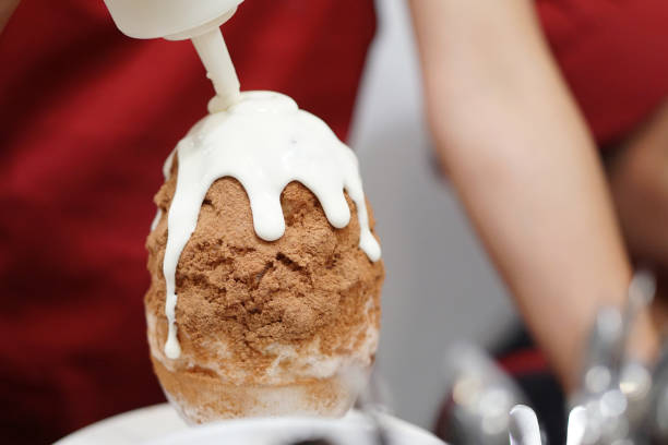 チョコレートカキゴリ作りのクローズアップ - 日本のかき氷デザート風味(ビングス)と白いクリームソース。 - かき氷シロップ ストックフォトと画像