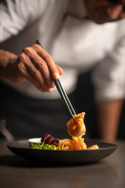 Closeup of male chef in restaurant decorates  the meal stock photo