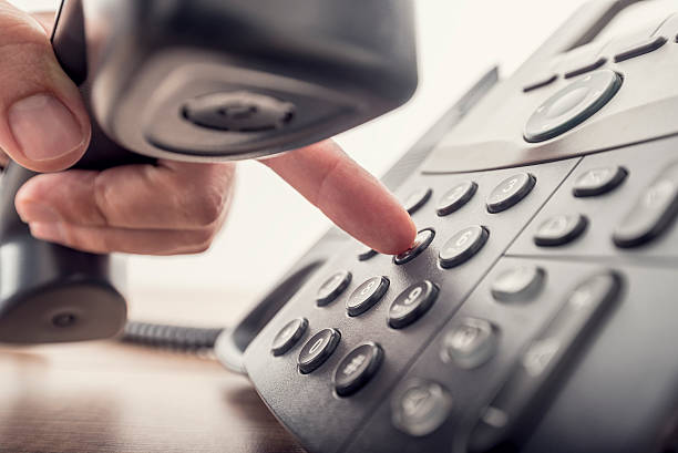 Closeup of male hand holding telephone receiver while dialing a stock photo