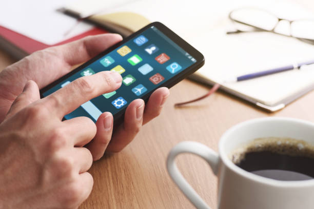 テーブルでアプリを使用するためのスマートフォンの画面に触れる男性の手のクローズアップ。 - スマホ　画面 ストックフォトと画像