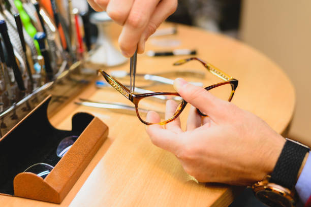 Closeup of male optician's hands repairing eyeglasses Closeup of adult caucasian male optician hands repairing eyeglasses using specialized tools lens optical instrument stock pictures, royalty-free photos & images