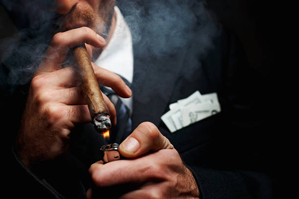 Close-up of man's hand with cigar and lighter Cropped image of a man lighting up a cigar gangster stock pictures, royalty-free photos & images