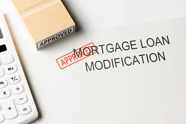 Close-up of mortgage modification with "Approved " rubber stamp with calculator Close-up of mortgage modification with "Approved " rubber stamp with calculator. Mortgage Renewals stock pictures, royalty-free photos & images