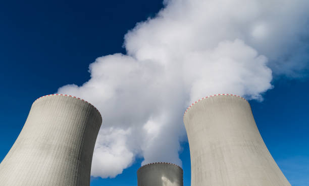 Closeup of nuclear power plant cooling towers belching out white plume of water vapor stock photo