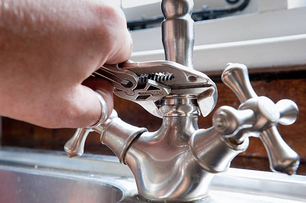 Close-up of plumber using wrench to fix faucet stock photo
