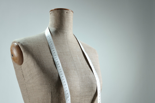 Close-up of retro female tailor's mannequin torso with measuring tape. Copy space. Processing for retro look, slight vignette added.