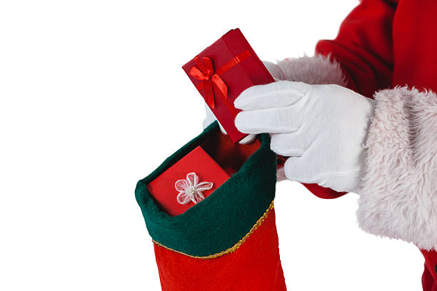 Close-up of santa claus putting presents Close-up of santa claus putting presents in christmas stockings against white background christmas stocking stock pictures, royalty-free photos & images