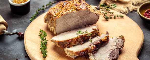 closeup of sliced roast pork with thyme herb mustard on a cutting picture - The Tasty Hub