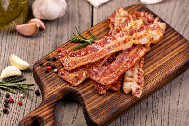 closeup of slices of crispy hot fried bacon - bacon imagens e fotografias de stock