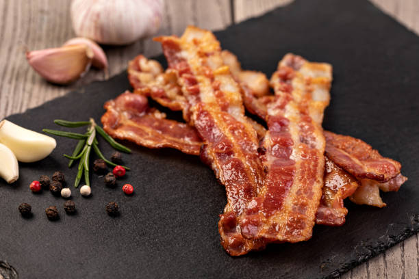 Closeup of slices of crispy hot fried bacon Closeup of slices of crispy hot fried bacon bacon stock pictures, royalty-free photos & images