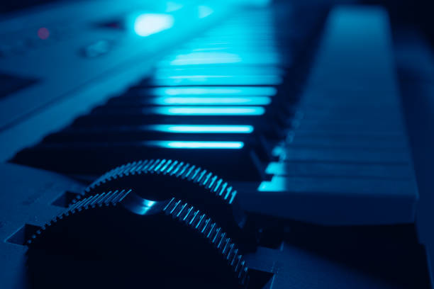 Closeup of synthesizer keyboard in dark ambient illuminated by blue light stock photo