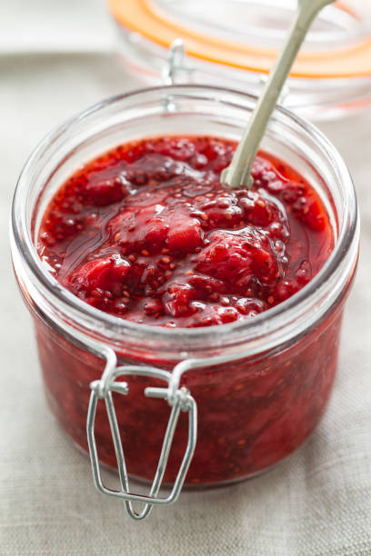 Closeup of tasty appetizing fruit strawberry jam with chia seeds in jar. Selective focus. stock photo