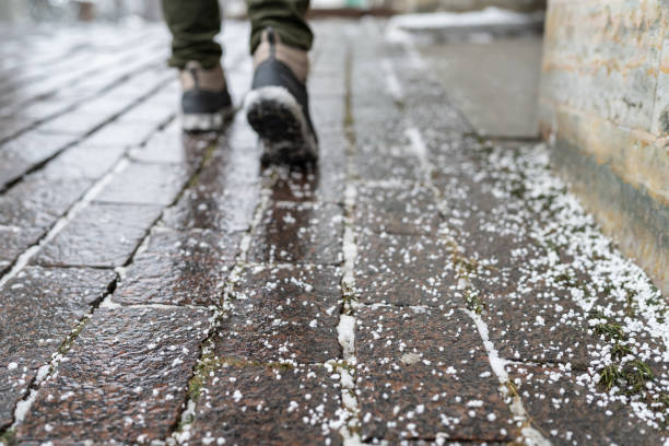Closeup of technical salt grains on icy sidewalk surface in winter, used for melting ice and snow. stock photo