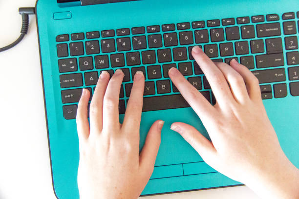 Closeup of teen girl hands on a laptop stock photo