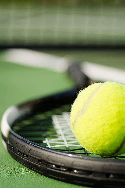 Close-up of tennis racket on court with tennis ball on top stock photo
