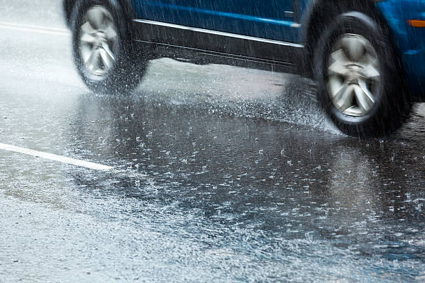Closeup of the ground where a car speeds past splashing rain stock photo
