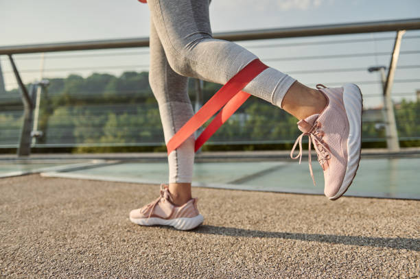 close-up of the legs of an athlete doing body weight training with a resistance fitness elastic band on a city bridge. - träningsgummiband bildbanksfoton och bilder