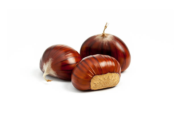 Close-up of three chestnuts on a white surface Small group of Chestnut with peel on white background chestnut food stock pictures, royalty-free photos & images