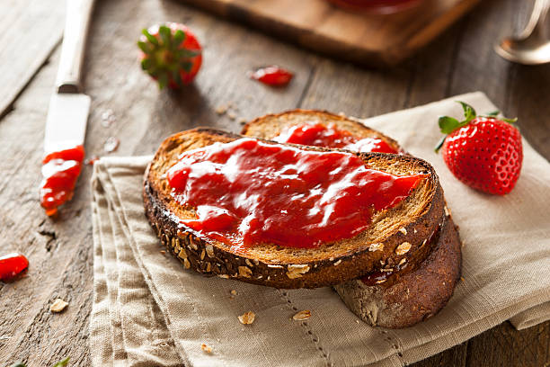 Close-up of toast with homemade strawberry jam on table Homemade Strawberry Jelly on Whole Wheat Toast toasted food stock pictures, royalty-free photos & images