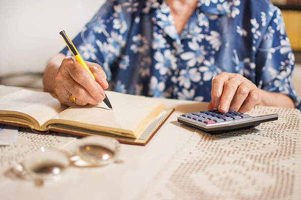 Close-up of unrecognizable senior woman doing finances at home. stock photo