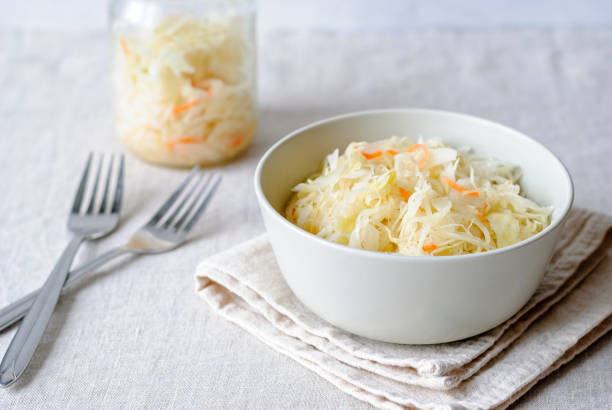 Closeup of white bowl with juicy sauerkraut served on napkin with forks stock photo