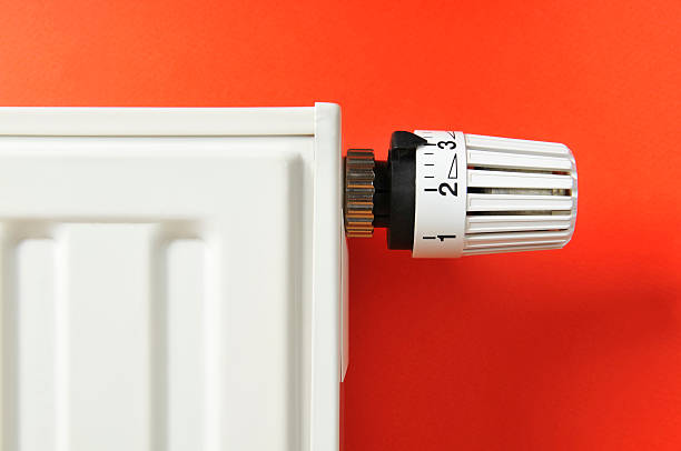 blanc gros plan d'un thermostat et radiateur sur fond rouge - chauffage photos et images de collection