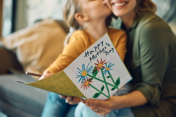 Close-up of woman receiving Mother's day greeting card from her daughter. stock photo