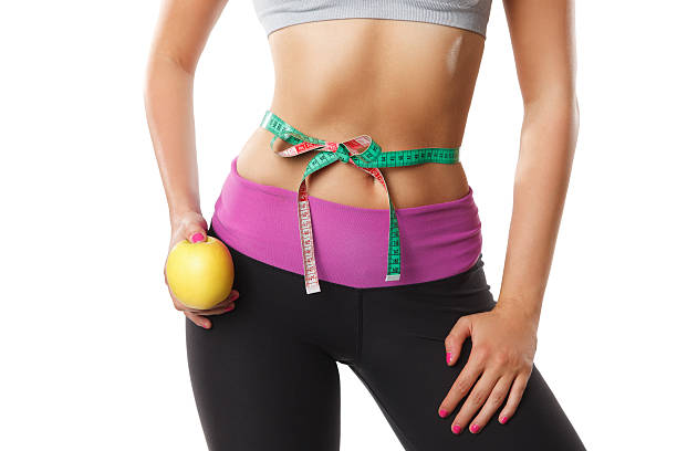 Closeup of woman stomach with measuring tape stock photo