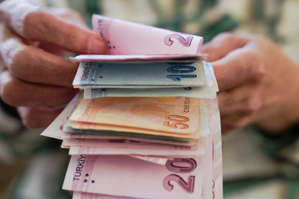 Closeup of wrinkled hands holding turkish lira banknotes stock photo