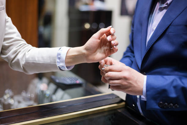 Close-up on elegant woman's hand, trying on luxurious jewelry Close-up on elegant woman's hand in position for trying on luxurious jewelry, clerk holding a piece to serve the customer store clerk selling jewelry stock pictures, royalty-free photos & images