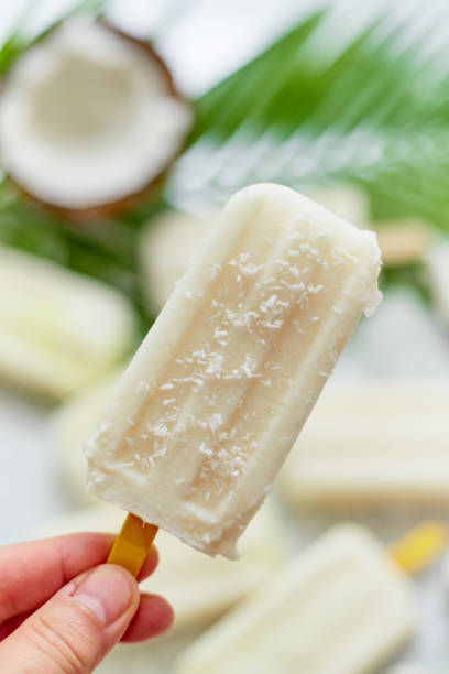 Closeup on hand holding homemade pineapple coconut popsicle. Summer food concept stock photo