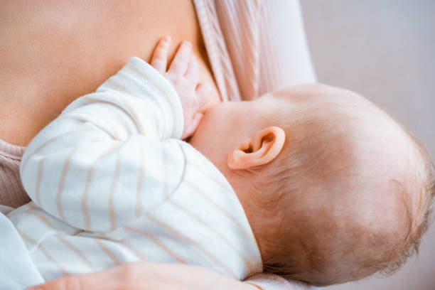 vista parziale ravvicinata della giovane madre che allatta il bambino - allattamento foto e immagini stock