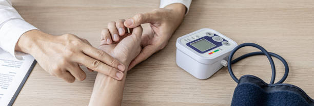 Close-up photo Doctor holding pulse on patient's wrist in the examination room, patient visits doctor due to discomfort. The concept of visiting a doctor when sick for a diagnosis. stock photo