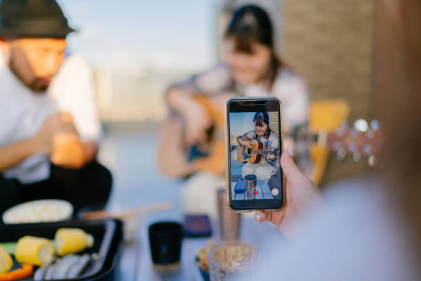 close-up photo of smart phone screen while friends enjoying listening to guitar - smartphone filming imagens e fotografias de stock