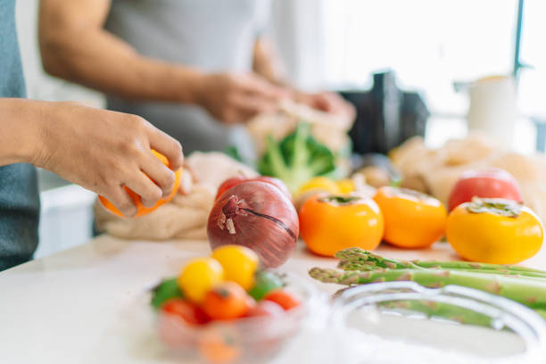 close-up foto van vrouw hand tijdens het bereiden van veganistisch eten thuis - eten koken stockfoto's en -beelden