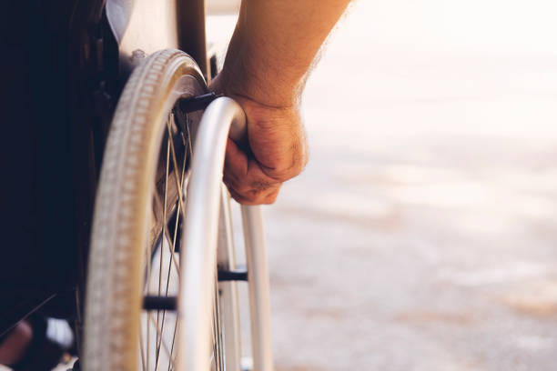 Closeup photo of Young disabled man holding wheelchair outside in nature stock photo