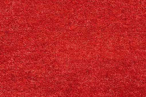 Red coloured textured carpet background viewed flat, from above.