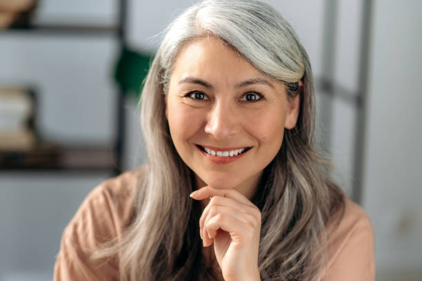 Close-up portrait of a beautiful successful mature asian business woman, self-confident gray haired lady in casual stylish wear, looking directly at the camera with friendly smile stock photo