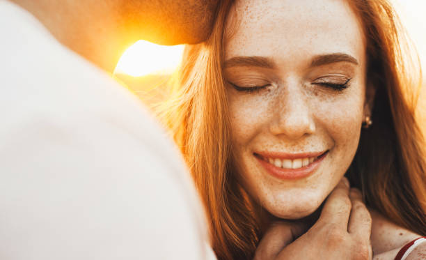 Close-up portrait of a happy freckled girl being kissed on the forehead by her husband. Travel concept. Close up portrait. Wheat field. stock photo