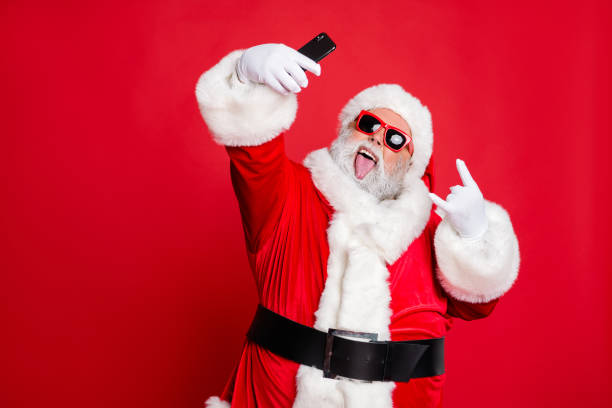 close-up portrait of his he cheerful cheery glad crazy cool funky fat overweight plump gray-haired bearded man taking selfie showing horn sign isolated over bright vivid shine red background - smartphone christmas imagens e fotografias de stock