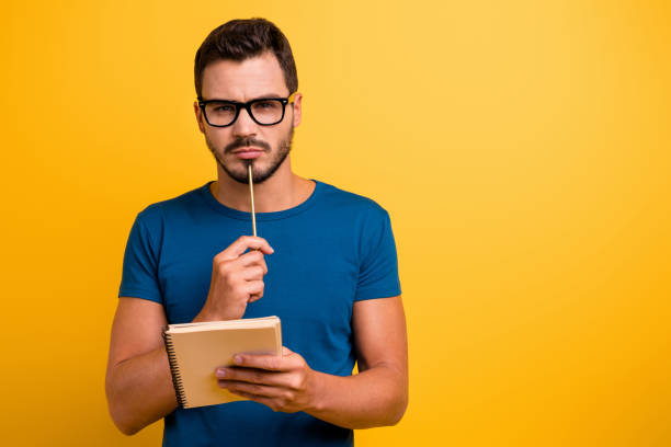close-up portrait of his he nice attractive focused concentrated intelligent guy writing notes creating new strategy isolated over bright vivid shine vibrant yellow color background - man with pen imagens e fotografias de stock