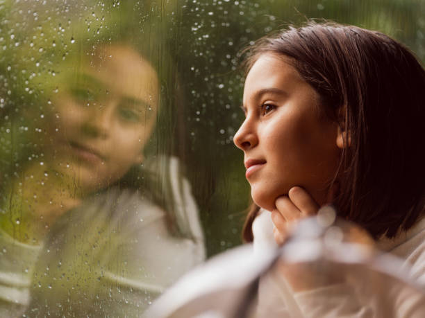 Close-up Portrait of Little Girl Next to Rainy Window stock photo