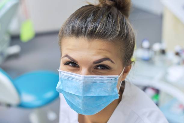 closeup portrait of smiling female dentist doctor in protective medical mask - aluno dentista imagens e fotografias de stock