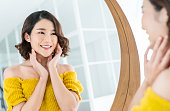 コピースペースとメイクアップルーチンのための鏡を持つ若い美しいアジアの女の子のクローズアップ肖像画。完璧な輝きの肌を持つ美容女性は黄色でドレスアップ。ヘルスケア女性ライフ�