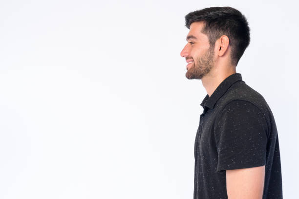 Closeup profile view of happy young bearded Persian man smiling Studio shot of young handsome bearded Persian man isolated against white background one young man only stock pictures, royalty-free photos & images